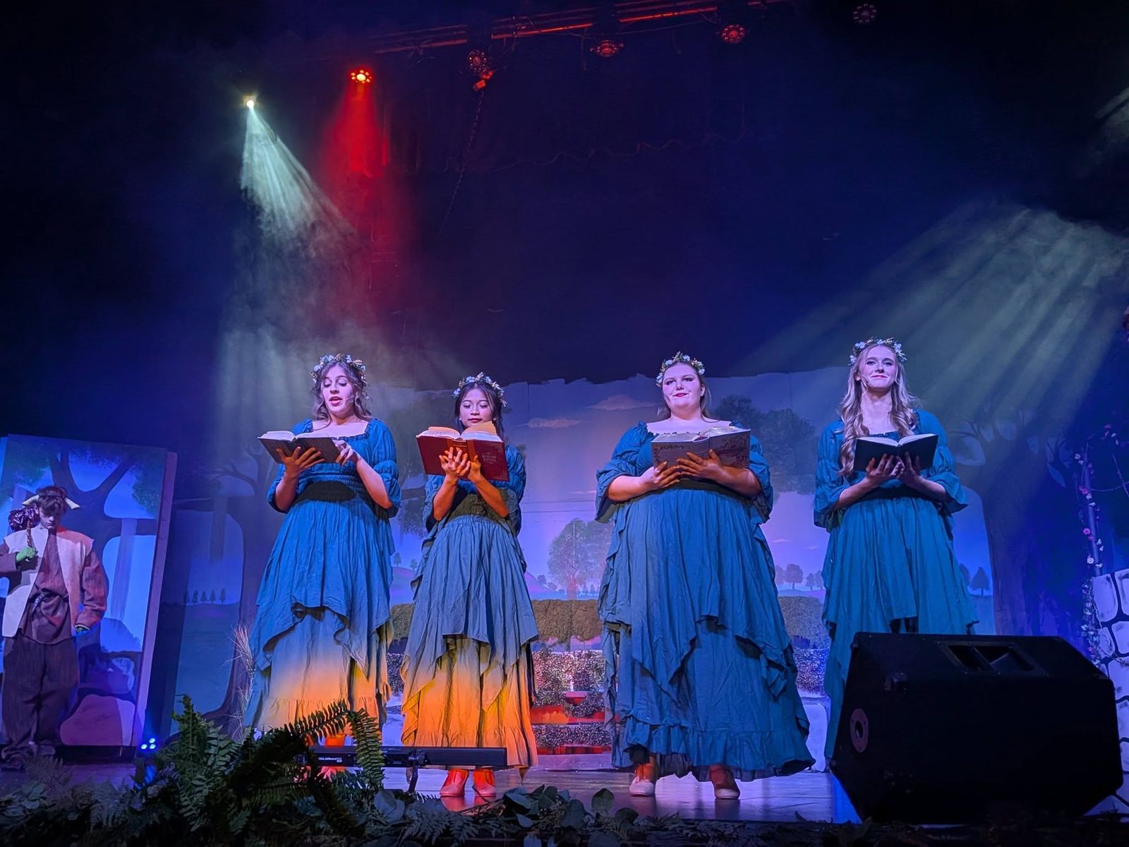 Four performers singing under blue and red stage lights