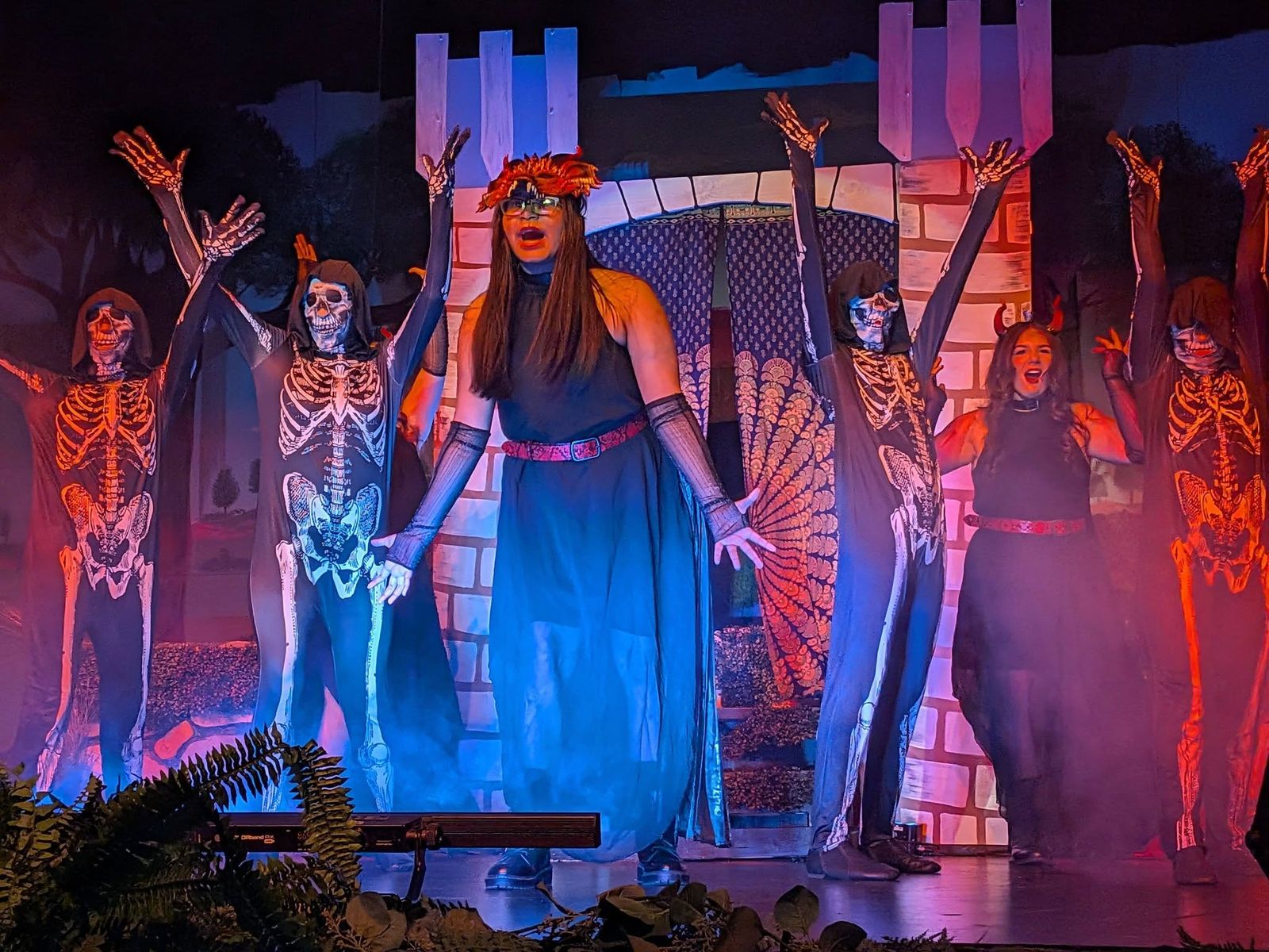 Dancers in glowing skeleton costumes around a performer in a blue gown